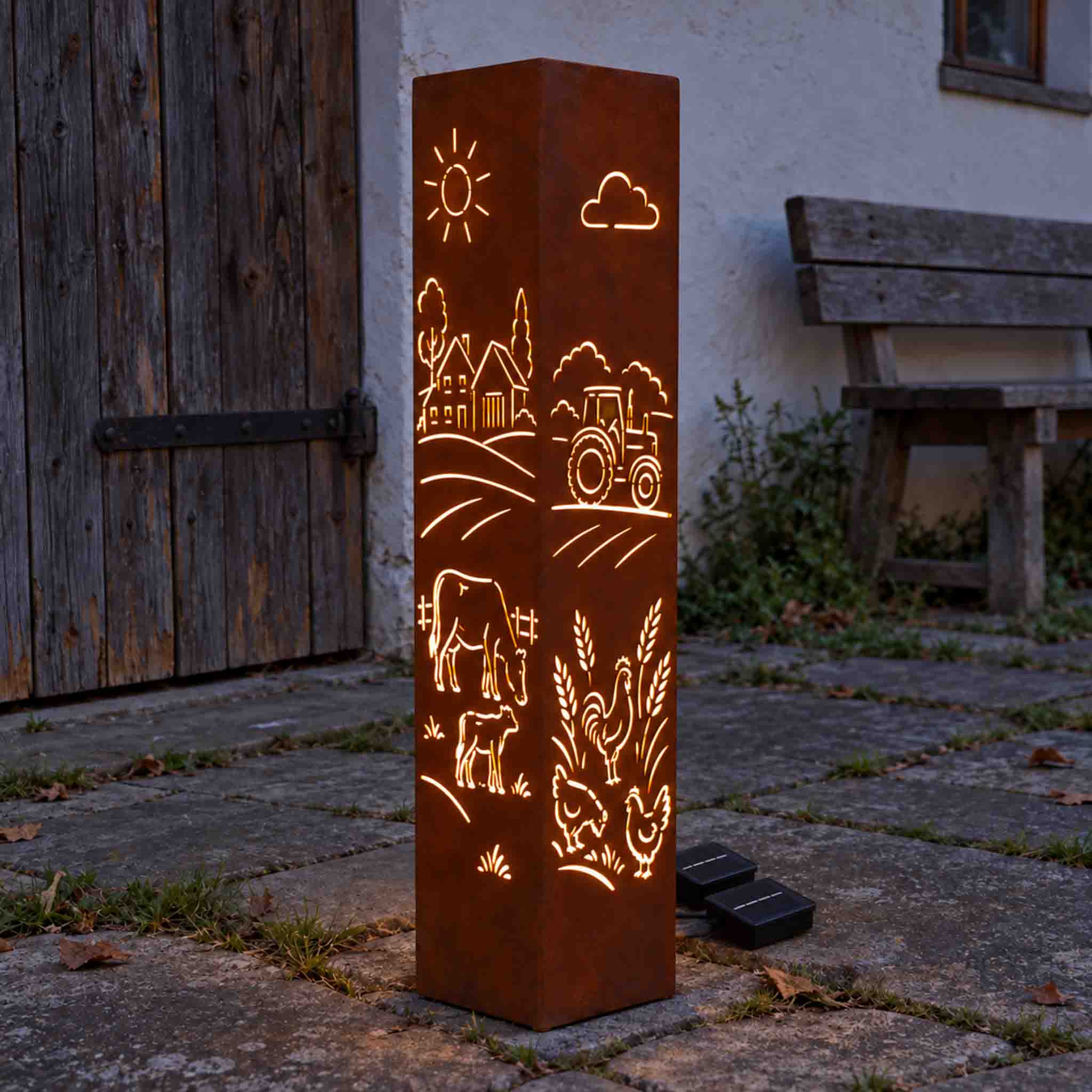 Bauernhof Säule aus Cortenstahl beleuchtet – Edelrost Stele mit Landleben-Motiv vor Holzwand.