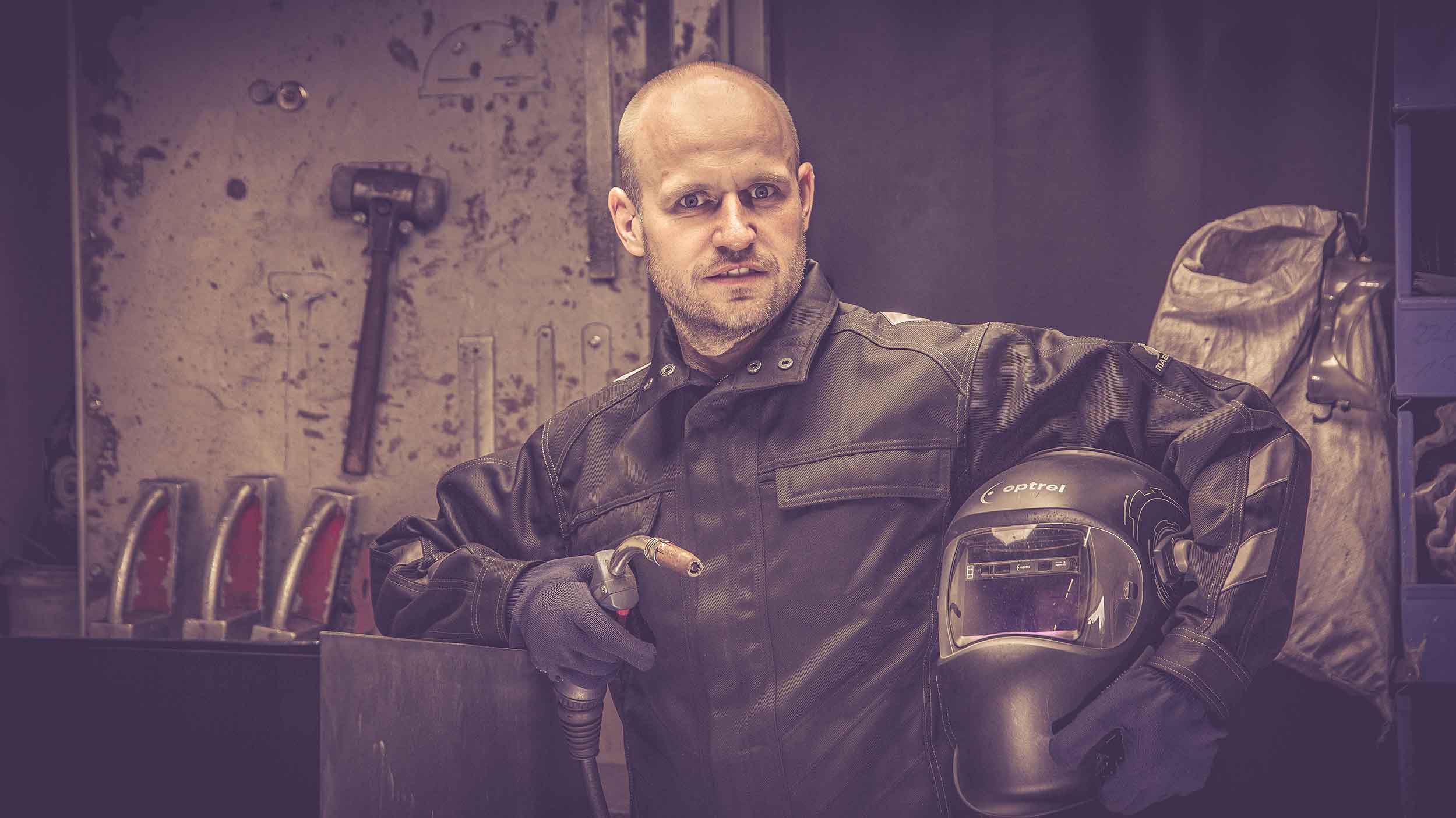 Jürgen, ein erfahrener Handwerker bei Rostikal, hält Schweißgerät und Schweißhelm, bereit für qualitativ hochwertige Metallbearbeitung