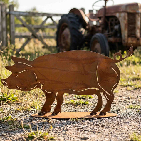Deko Schwein aus Cortenstahl auf dem Bauernhof – Gartenfigur vor Zaun und Traktor