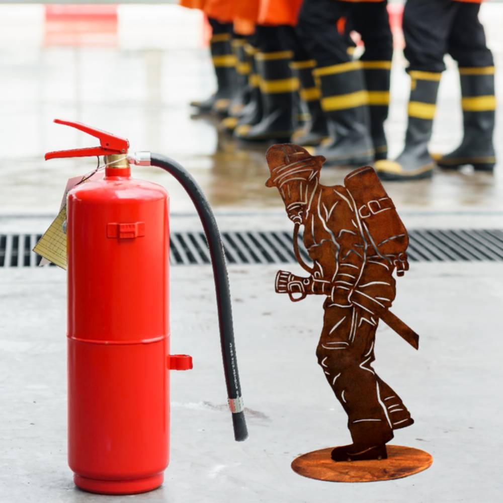 Rostige Metall Feuerwehrmann Skulptur auf Bodenplatte als wetterfeste und langlebige Dekoration für den Garten und den Wohnbereich.
